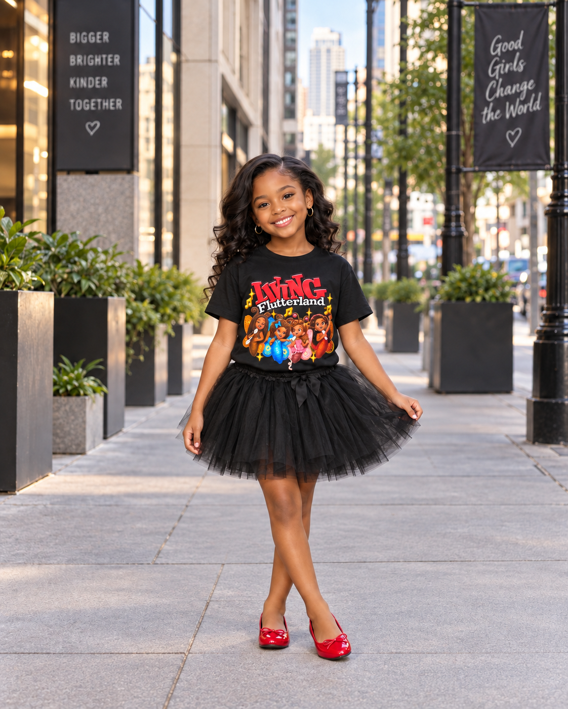 A young girl stands on a city sidewalk modeling a black graphic t-shirt featuring the 'King Kong' movie print, paired with a black tulle tutu skirt and red shoes.